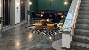Eine großzügige Lobby mit einer Treppe, einer Sitzecke mit Poufs und einer grünen Akzentwand.