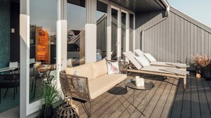 Eine Terrasse mit einer Couch, zwei Liegestühlen und einem Couchtisch.