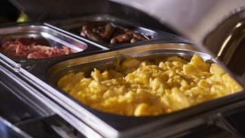 Buffet-pöydässä on tarjolla monipuolinen valikoima ruokia, kuten munakokkelia, makkaroita ja muita herkkuja.