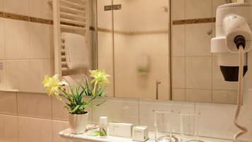 A bathroom with a white sink, a mirror, a towel rack, a potted plant, and a hairdryer.