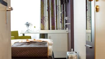Una habitación de hotel con cama, maleta, escritorio con silla y televisión.