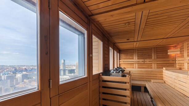 A sauna room with wooden benches and a view of the cityscape through large windows. - Thon Hotel Brussels City Centre (Brussels)