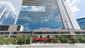 A modern high-rise building with reflective glass windows and a prominent entrance with a red awning. - Thon Hotel Brussels City Centre (Brussels)