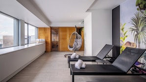 A modern room with large windows, a hanging chair, and two lounge chairs with towels. - Thon Hotel Brussels City Centre (Brussels)