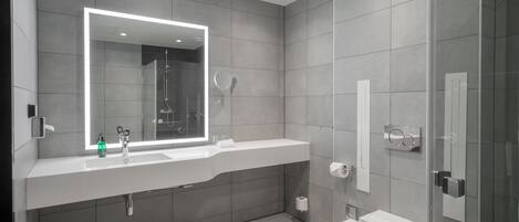 Un baño moderno con un espejo grande, una ducha, un inodoro y un lavabo.