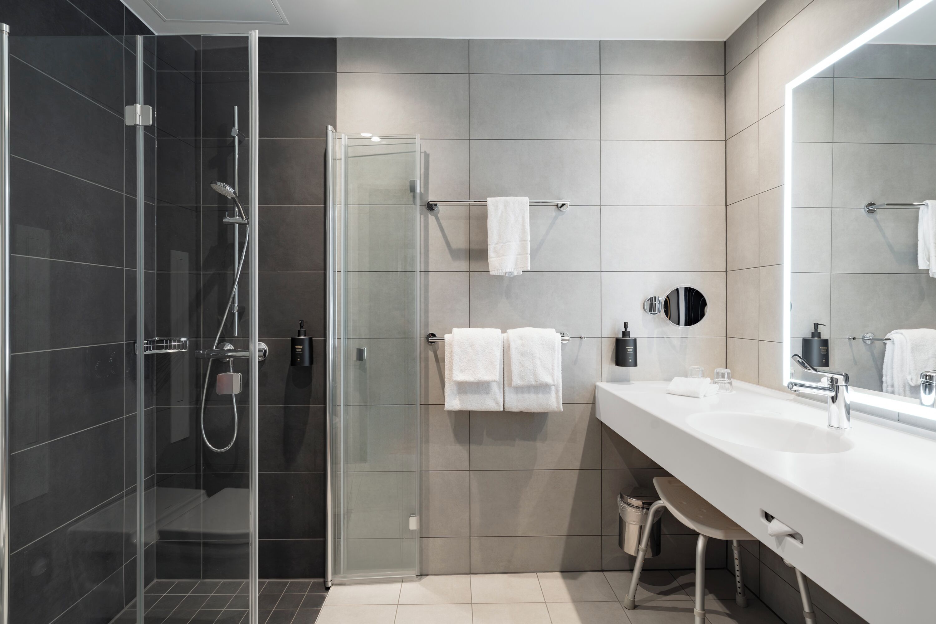 A modern bathroom with a glass shower enclosure, a white sink, and a large mirror.