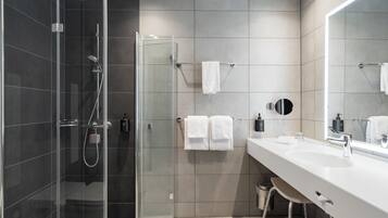A modern bathroom with a glass shower enclosure, a white sink, and a large mirror.