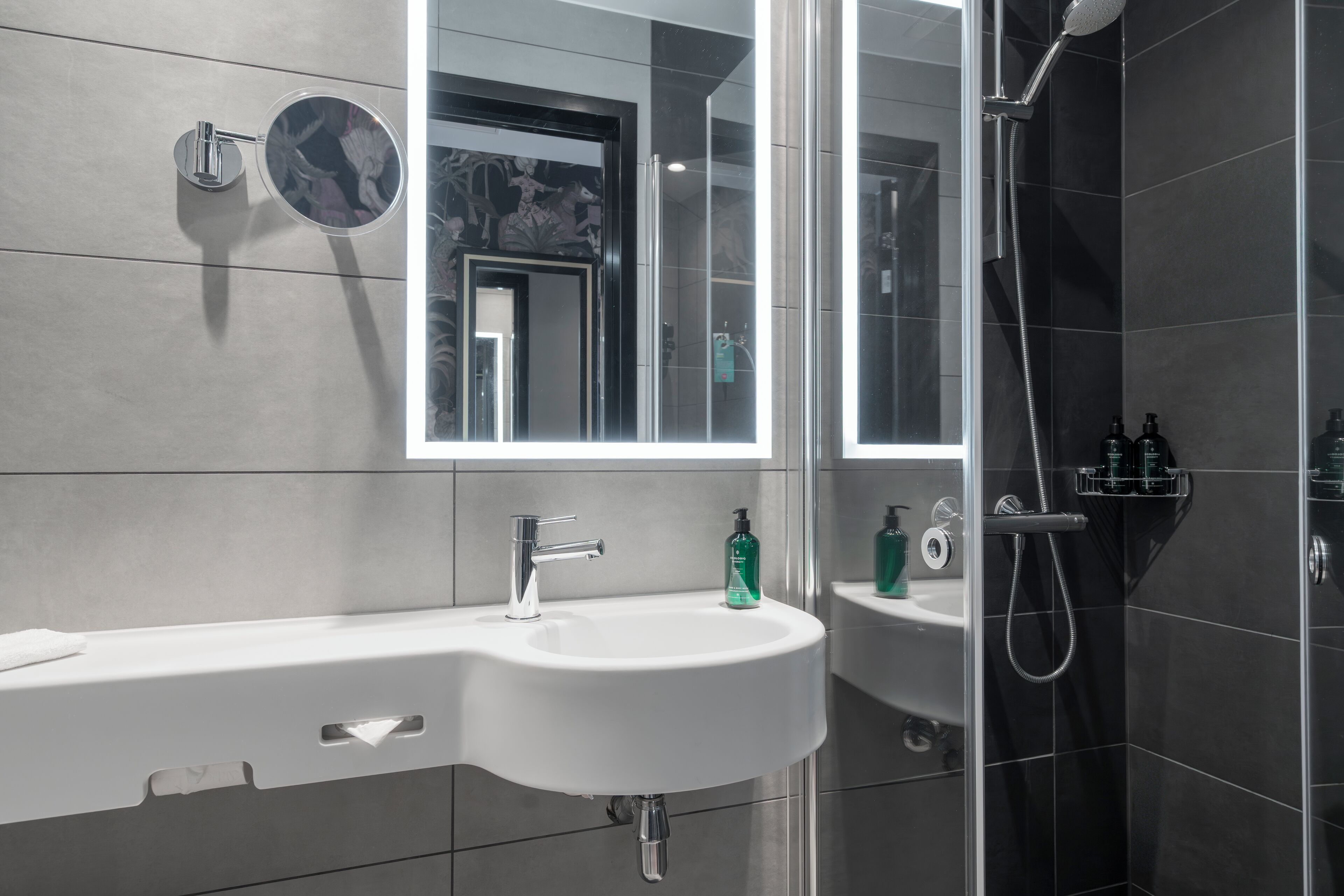 A modern bathroom with a sink, mirror, and shower.