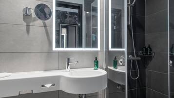 A modern bathroom with a sink, mirror, and shower.