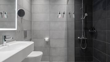 Un baño moderno con lavamanos, inodoro y ducha.