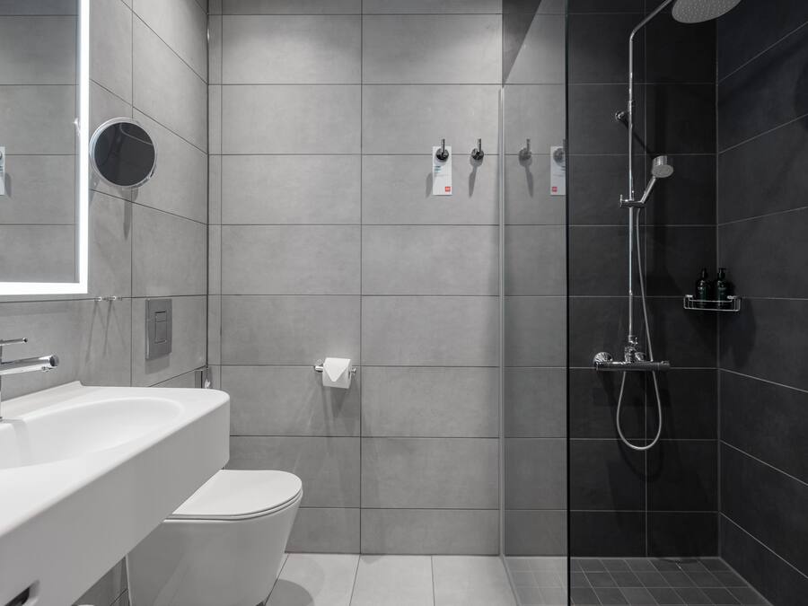 Un baño moderno con lavamanos, inodoro y ducha.