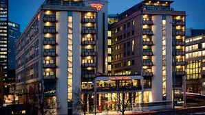 Een modern hotelgebouw met meerdere verdiepingen en balkons, met een opvallend 'Thon Hotel Opera' bord.