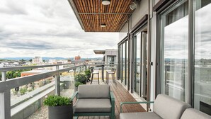 A balcony with seating, a potted plant, and a city view. - Thon Hotel Opera (Oslo)