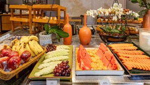 Un bufé con diversas frutas y verduras, incluyendo plátanos, manzanas, uvas, sandía y zanahorias.
