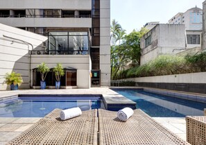Una piscina al aire libre, sillones reclinables de piscina