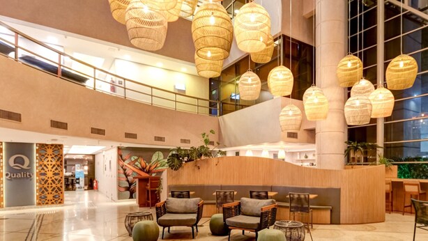 Un hall amplio con mostrador de recepción, asientos cómodos y lámparas decorativas de mimbre.