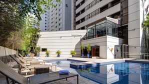 Un área de piscina moderna al aire libre con sillones de descanso, una piscina pequeña y plantas en macetas.