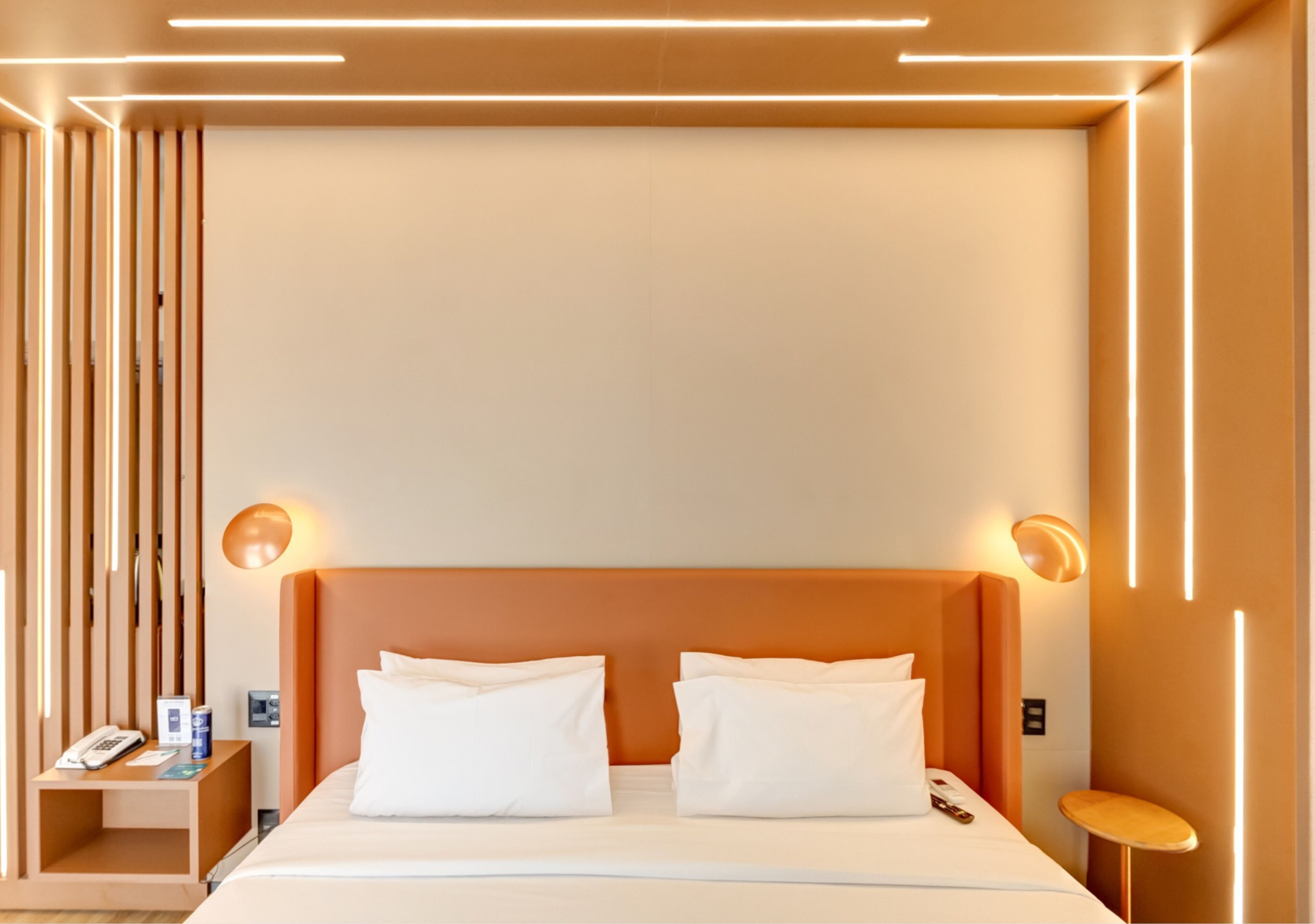 Una habitación de hotel moderna con una cama grande, dos mesitas de noche y una mesita auxiliar.