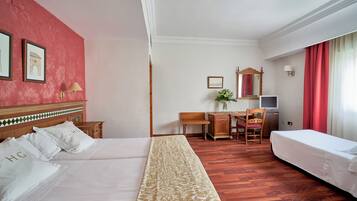 Habitación de hotel con dos camas, un escritorio con silla, un televisor y un espejo.