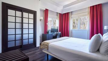 Habitación de hotel con cama, escritorio y televisión.