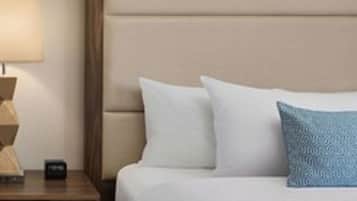 A hotel room with a bed, a nightstand, a lamp, and a blue pillow.