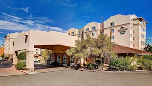 A hotel with a covered entrance, multiple floors, and a flag. - Homewood Suites by Hilton Albuquerque Uptown (Albuquerque)