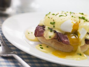 A plate of food with eggs, ham, and sauce. - Hilton Santa Clara (Santa Clara)