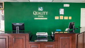 A hotel reception desk with a green wall, a Dell computer, and a cash register.