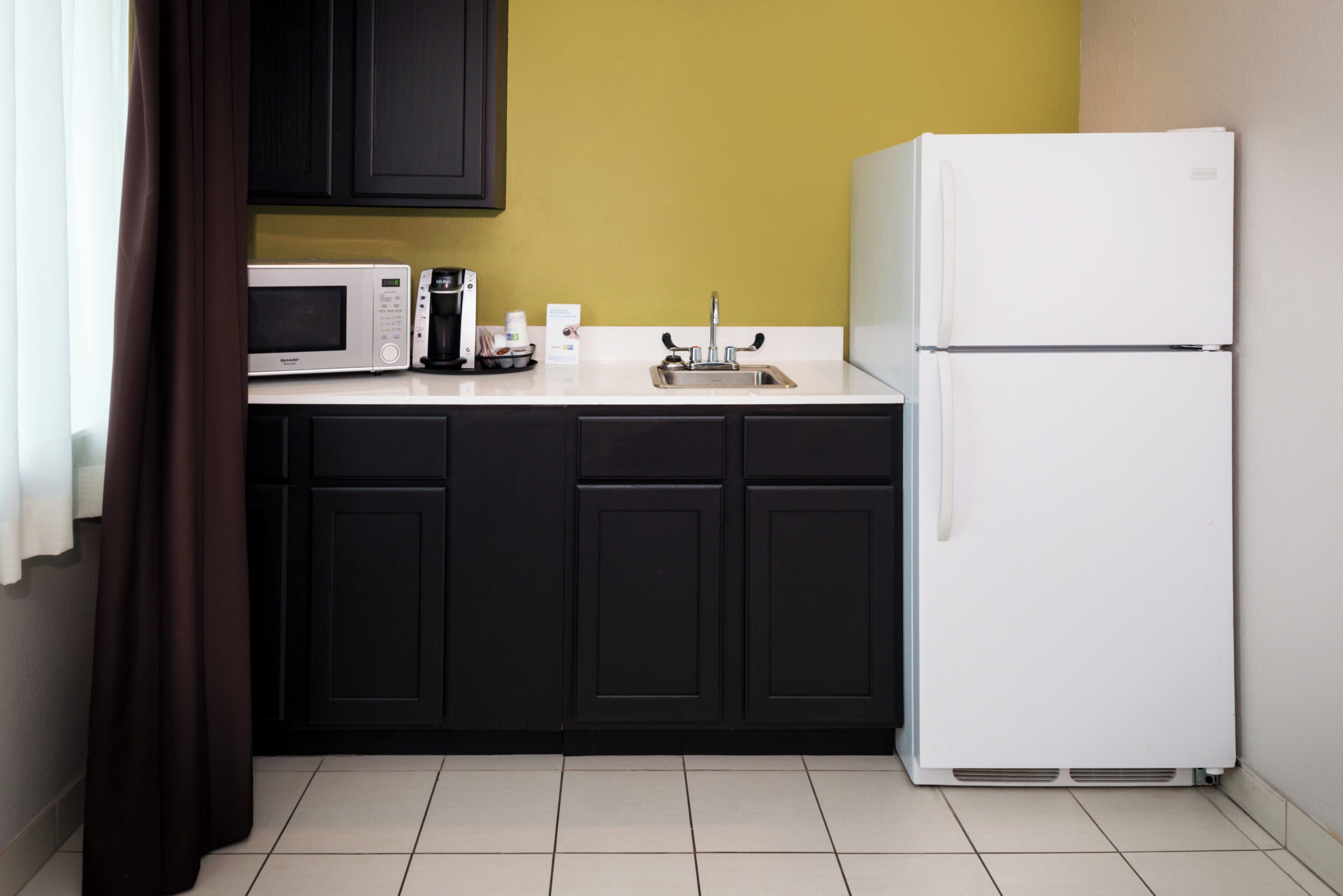 A kitchen with a microwave, coffee maker, and refrigerator.