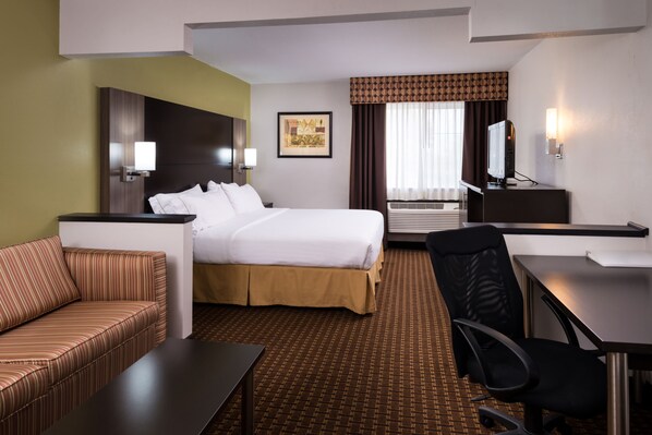 Quarto de hotel com cama, sofá, escrivaninha e cadeira.