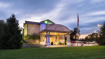 A Holiday Inn Express hotel with a covered entrance, flagpole, and parking lot.