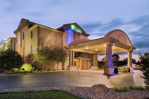 Un hôtel Holiday Inn Express doté d’une entrée abritée, d’une allée aménagée et d’un grand élément décoratif en roche.