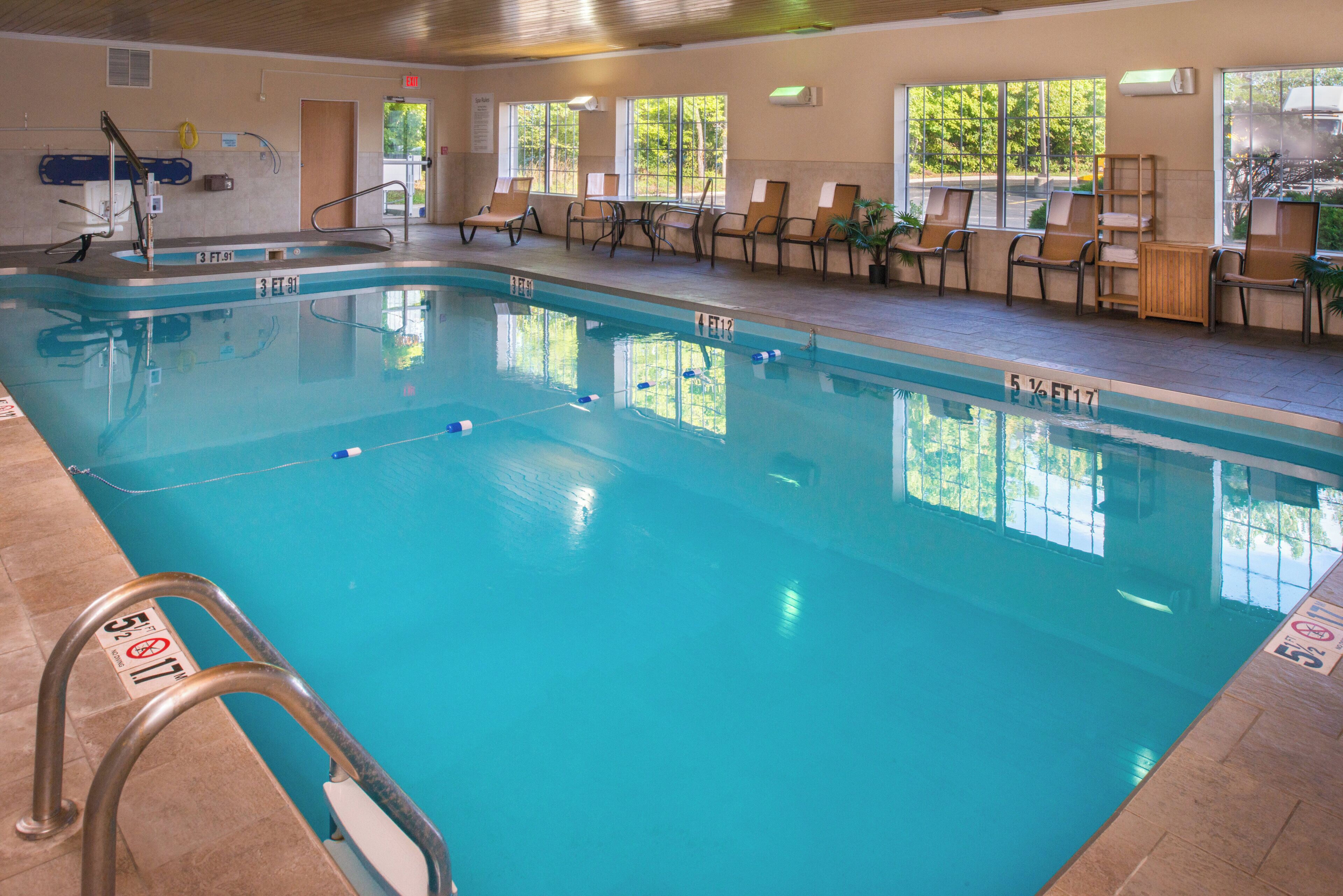 An indoor swimming pool with clear water, marked lanes, and a lifeguard stand.