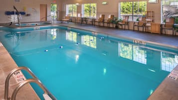 An indoor swimming pool with clear water, marked lanes, and a lifeguard stand.