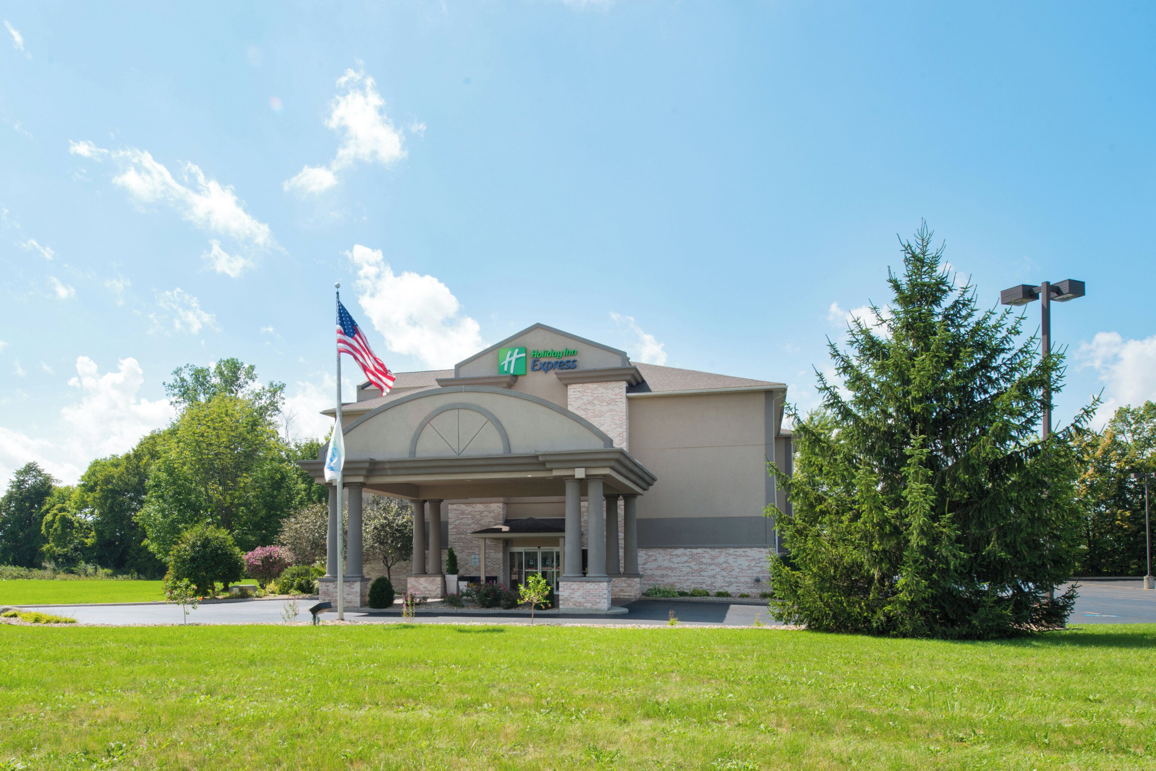 A Holiday Inn Express hotel with a brick facade, an American flag, and a covered entrance.