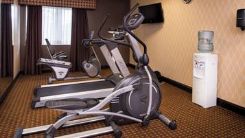 Une chambre d’hôtel équipée d’appareils de musculation, notamment un tapis de course, un vélo elliptique et un vélo d’appartement.