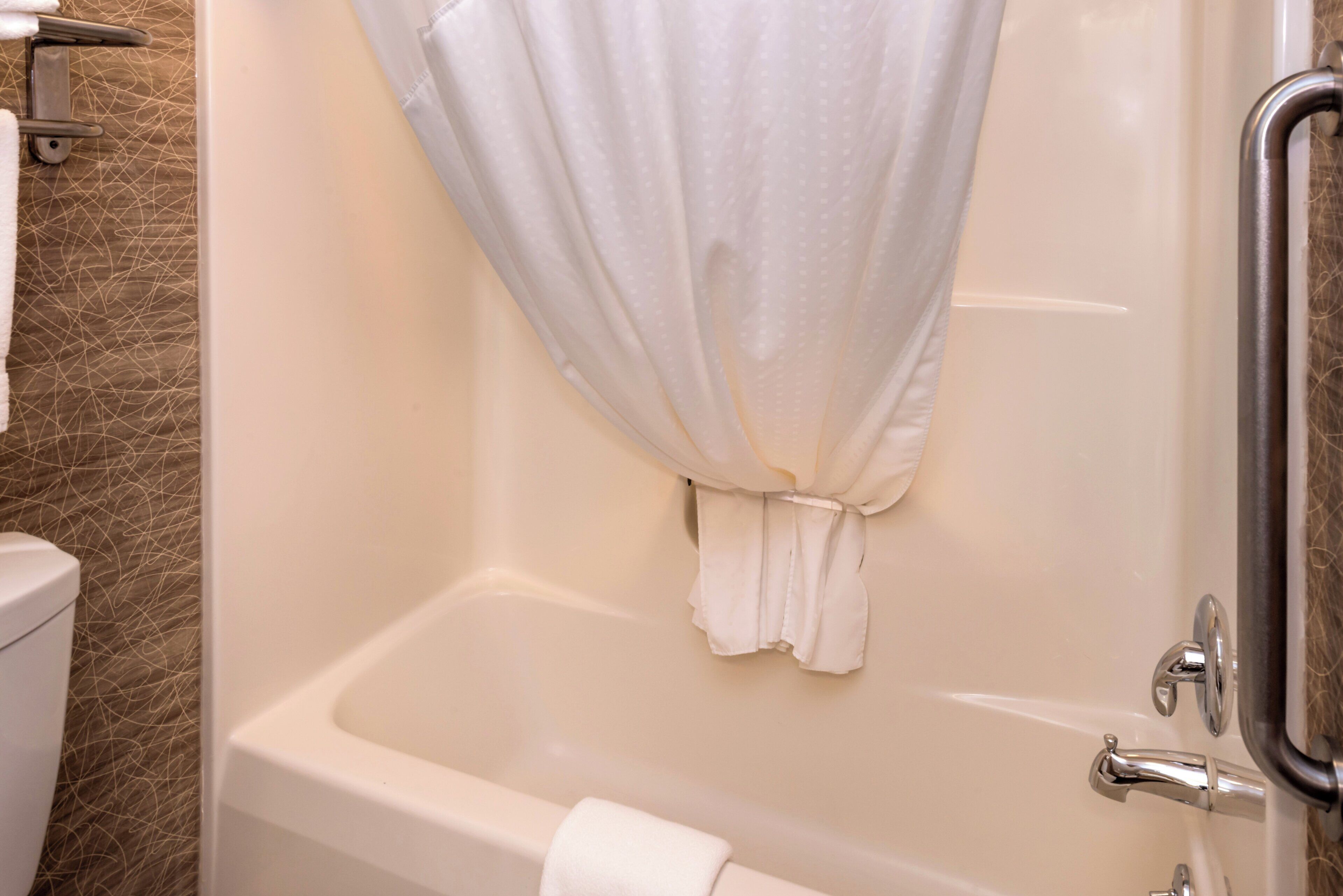 A bathroom with a bathtub, a toilet, and a shower area.