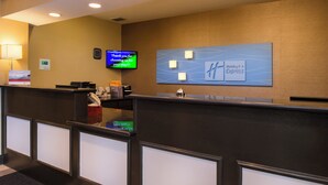 Una mesa de recepción de hotel con una pantalla digital mostrando un mensaje, un letrero de Holiday Inn Express y una barra de recepción.