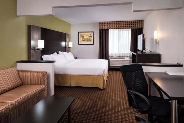 A hotel room with a bed, a desk, a chair, a sofa, and a television.