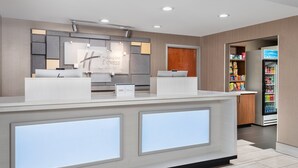 A hotel reception area with a modern design, featuring a reception desk, a sign for 'Express Suites', and a refrigerator stocked with snacks. - Holiday Inn Express Hotel & Suites Chattanooga-Lookout Mtn by IHG (Chattanooga)