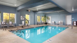 Una piscina con borde de azulejos azules, una escalera metálica y un cartel que indica zona sin saltos.
