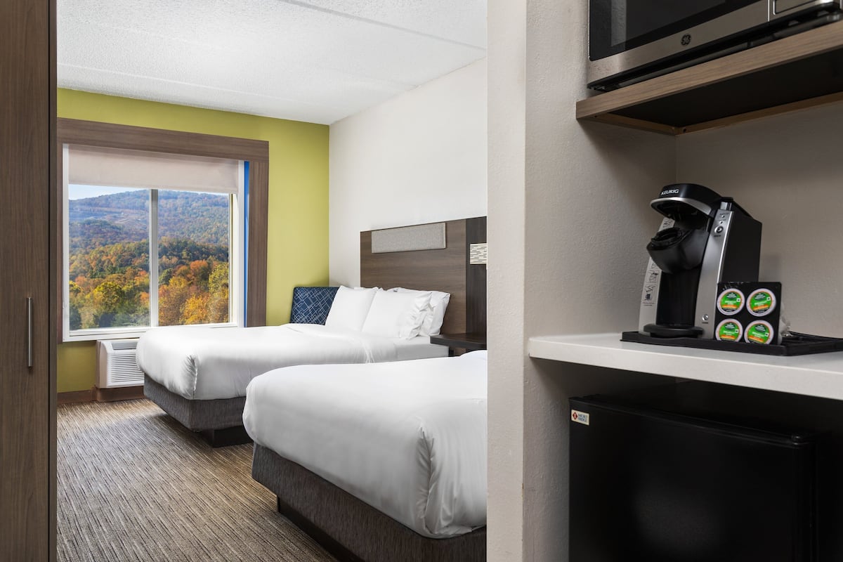Ein Hotelzimmer mit zwei Betten, einer Kaffeemaschine und Blick auf herbstliches Laub.