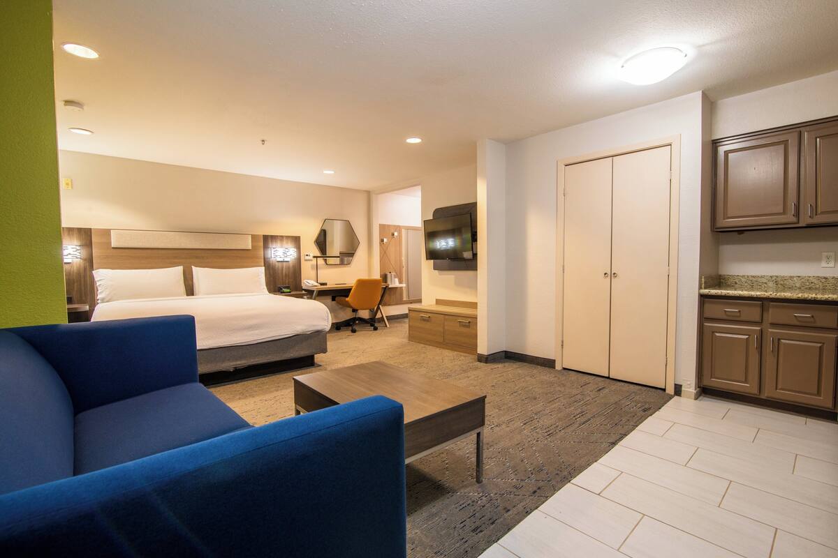 A hotel room with a bed, a desk, a chair, a coffee table, and a TV.