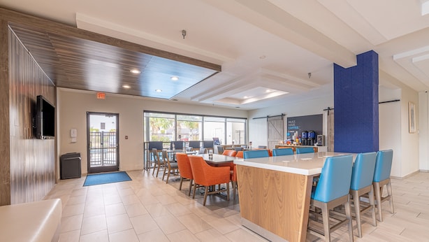 A modern dining area with a central island, orange chairs, and a blue accent wall.