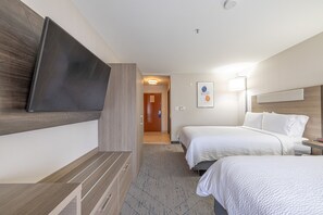 A hotel room with two beds, a flat-screen TV mounted on the wall, a bedside table, and a lamp. - Holiday Inn Express & Suites College Station by IHG (College Station)