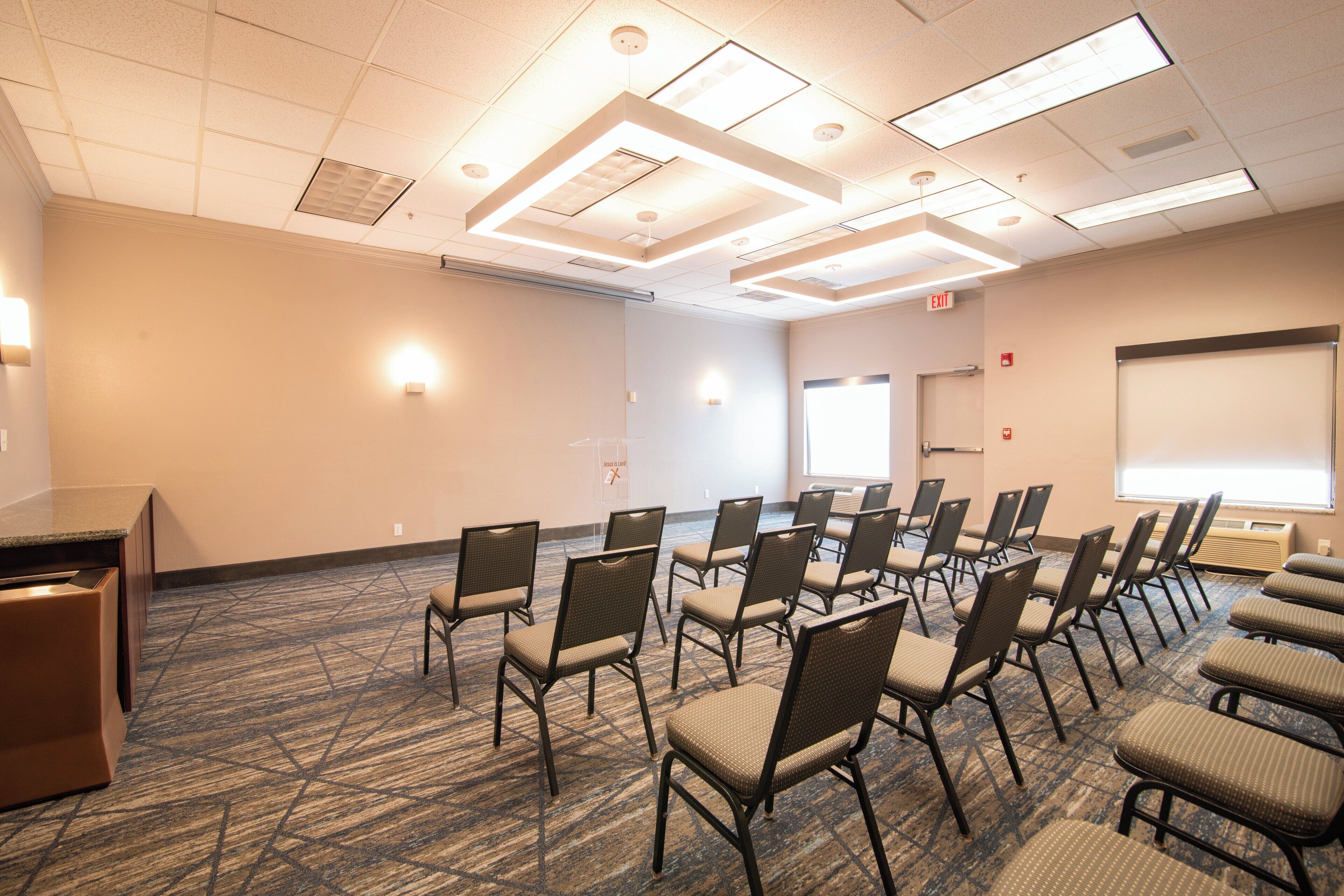 A conference room with rows of chairs, a podium, and a projector screen.
