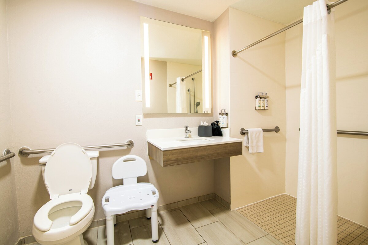 Un baño con inodoro, lavamanos, espejo y zona de ducha.