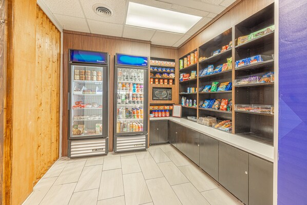 Espaço de lanches com autosserviço, com prateleiras refrigeradas e não refrigeradas, abastecidas com diversos alimentos.