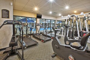 Une salle de sport équipée de tapis de course, de vélos elliptiques et de matériel de musculation.