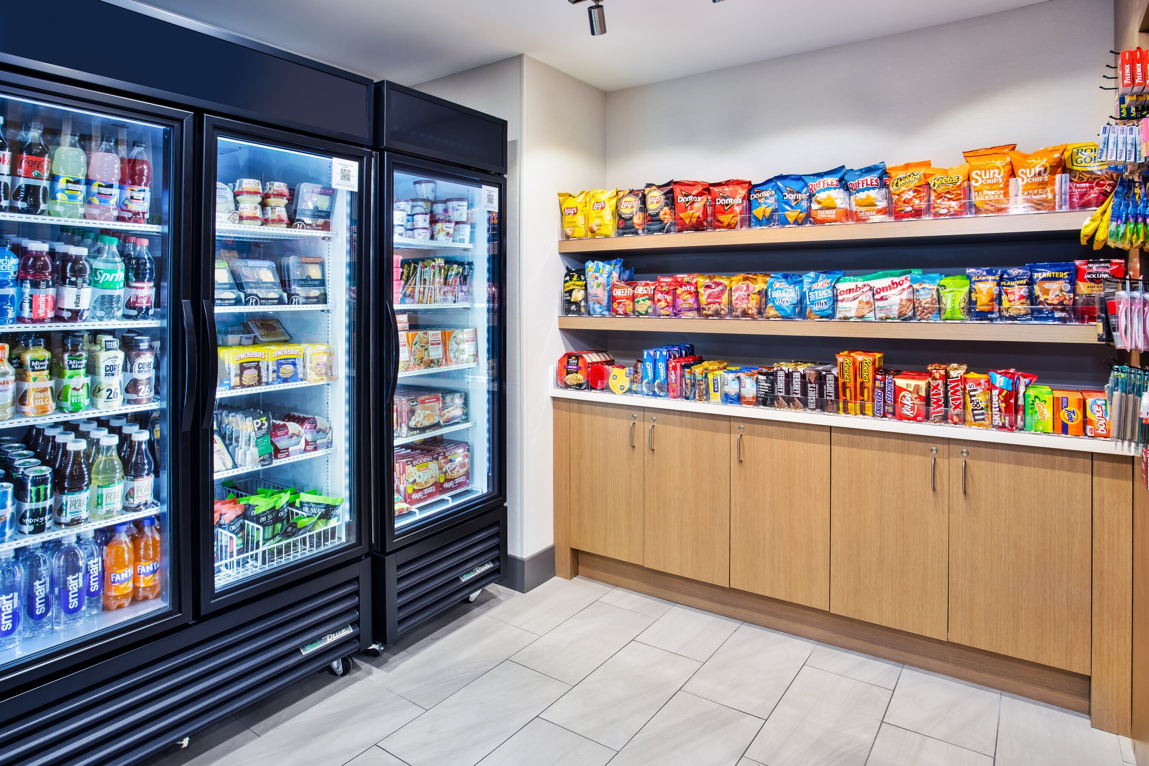 A well-stocked snack and beverage section with refrigerated drinks and a variety of snacks on shelves.